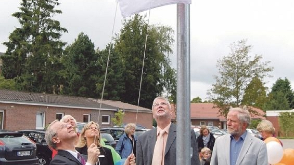 Landrat Bernhard Bramlage hisst die Flagge des Familienstützpunktes. Daneben Karlheinz Hinderks, stellvertretender Bürgermeister, und Fritz Wessels, für die SPD im Kreistag. © Foto: Hoegen 