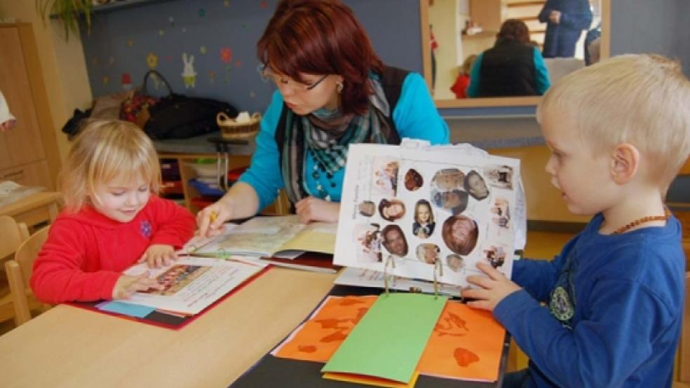 Mara und Bennet schmökern in ihren Portfolio-Ordnern. Darin sind ihre »gesammelten Werke« aus dem Kindergarten abgeheftet. Erzieherin Kathrin Müller hat dazu ihre »Baum-Bücher« vor sich liegen und zeigt, welcher Punkt mit welchem »Werk« abgehakt wurde. © Foto: Nagel