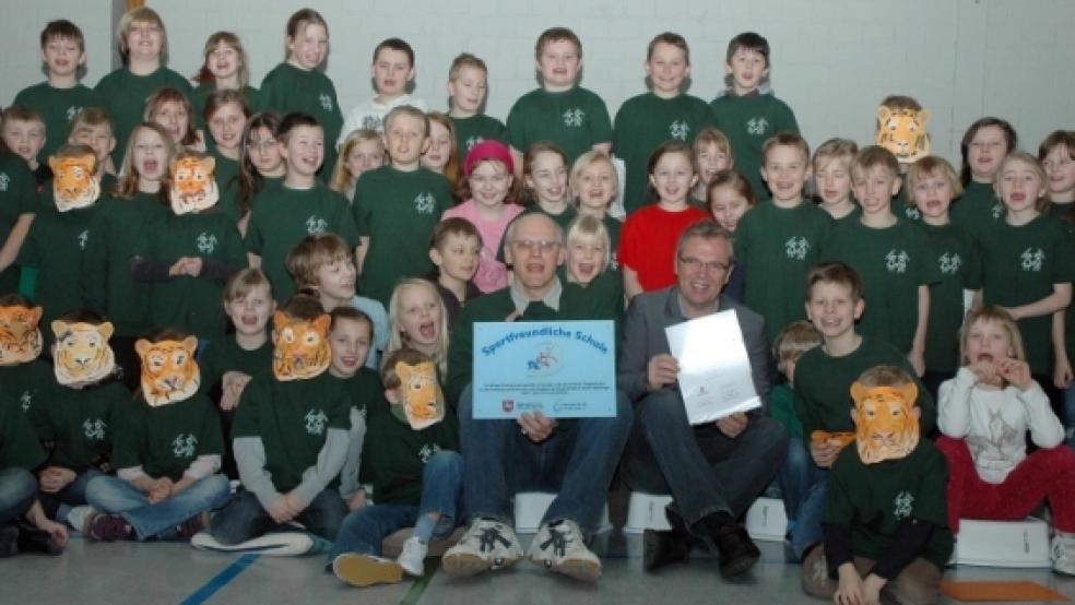 In die Mitte genommen wurden Schulleiter Gerrit Wilke (links) und Tom Bohmfalk von der Landesschulbehörde, der die Auszeichnung überreichte, von den Schülerinnen und Schülern der Grundschule Bingum. © Fotos: Mentrup