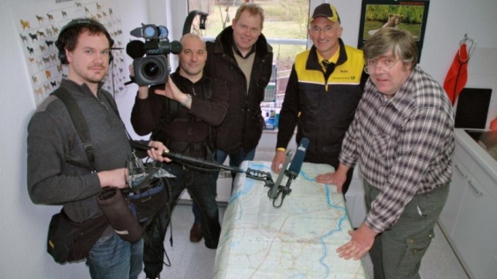 Die Besonderheiten des Rheiderlands ließen sich Ton-Assistent Sebastian Beck, Kameramann Reinhard Bettauer und Produzent Johann Ahrends gestern vom Weeneraner Postboten und RZ-Fotografen Jan Bruins und vom Holthuser Tierarzt Dr. Gerd Dodenhof auf einer Landkarte zeigen (im Bild von links). © Foto: Szyska