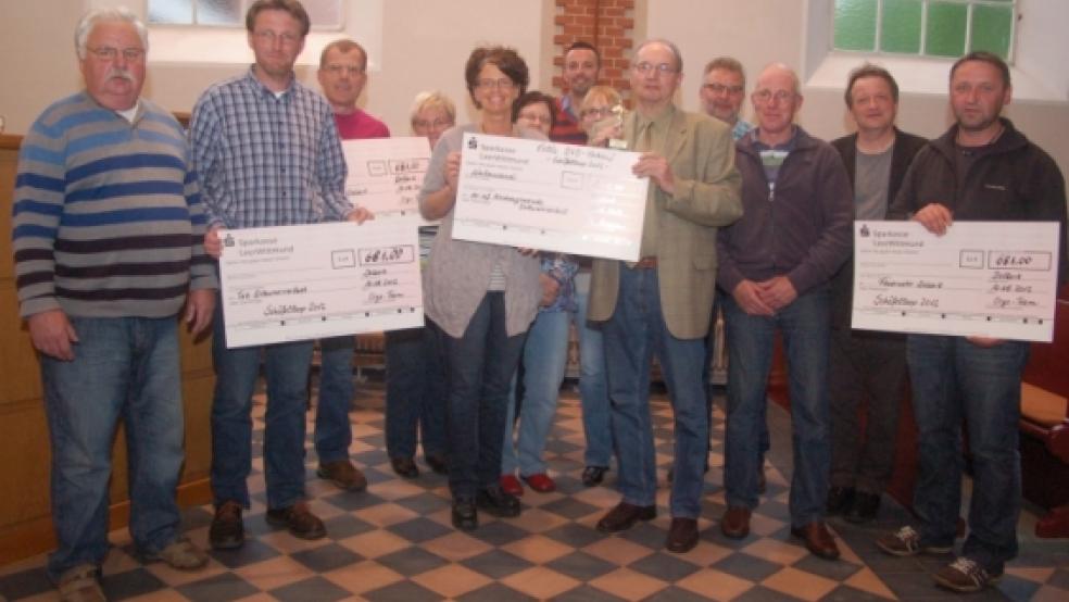 Ortsvorsteher Kurt Vohs, Jens Watermülder, Hans Tülp, André Woldendorp, Karin Mertens, Petra Freyborg-Veenhuis, Reinhard Aeissen, Okko Veenhuis, Lübbert Heikens, Pastor Jürgen van den Wieren und Ortsbrandmeister Uwe Röttmann bei der Scheckübergabe auf den neu verlegten Fliesen in der ev.-ref. Kirche Ditzumerverlaat.  © Jansen