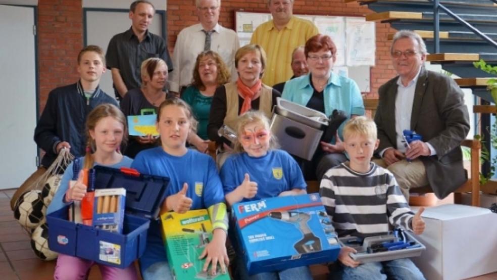 Über die Sachspenden, die (hinten von links) Hartmut Waddenberg, Dieter Gottwald und Joachim Bugiel vom Gewerbeverein Jemgum überreichten, freuten sich (Mitte von links) Hauke Bugiel (C-Jugend SV »Ems« Jemgum), Sylvia Plöger (Kindergarten Midlum), Emmi Gronewold (Mühlenverein Jemgum), Karin Hinderks (Dorfverein Midlum), Stefan Sinning (Mühlenverein Jemgum), Maria van Rüschen (Dorfverein Midlum) sowie Schulleiter Wolfgang Philipps mit Grundschülern im Vordergrund.  © Foto: Wübbena