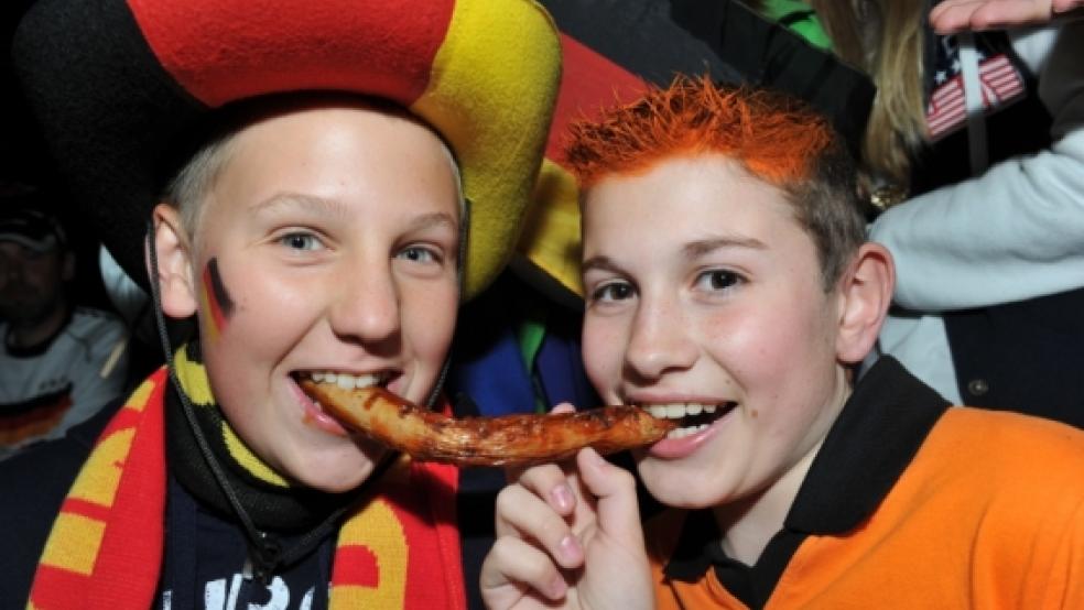 Geteilt wie diese Bratwurst wurden die Punkte im EM-Spitzenspiel Deutschland gegen die Niederlande nicht - was den meisten Teilnehmern des RZ-Tippspiels zu Gute kam. In der Landsburghalle in Weener herrschte gute Stimmung während der Übertragung des Topspiels. Sven (links) und Marc (der Möhlenwarfer ist gebürtiger Holländer) zeigen, wie gut sich die Nachbarländer außerhalb des Spielfelds verstehen können. Foto: Bruins © Bruins