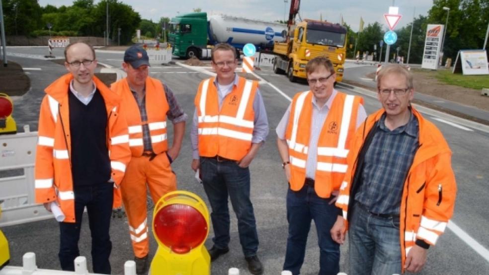 Machen den Weg frei: (von links) Aart Viétor (Straßenbaubehörde Aurich), Axel Löning (Straßenmeisterei), Frank Timmer und Torsten Brinker von der Firma Bunte sowie Detlef Penning (Straßenbaubehörde Aurich) besiegelten gestern die Freigabe des Weeneraner Kreisels (im Hintergrund). Seit heute Morgen soll hier der Verkehr rollen. © Fotos: Hanken