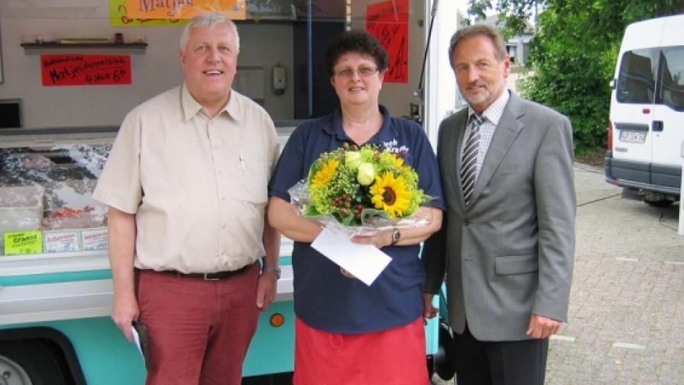 Fischverkäuferin Johanne Jakobs wird auf dem Wochenmarkt in Weener fehlen. Mit einem Strauß Blumen dankten ihr für viele Jahre im Wagen von »Fisch Kramer« Bürgermeister Wilhelm Dreesmann (re.) sowie Marktmeister Gerold van Hoorn. © Foto: privat