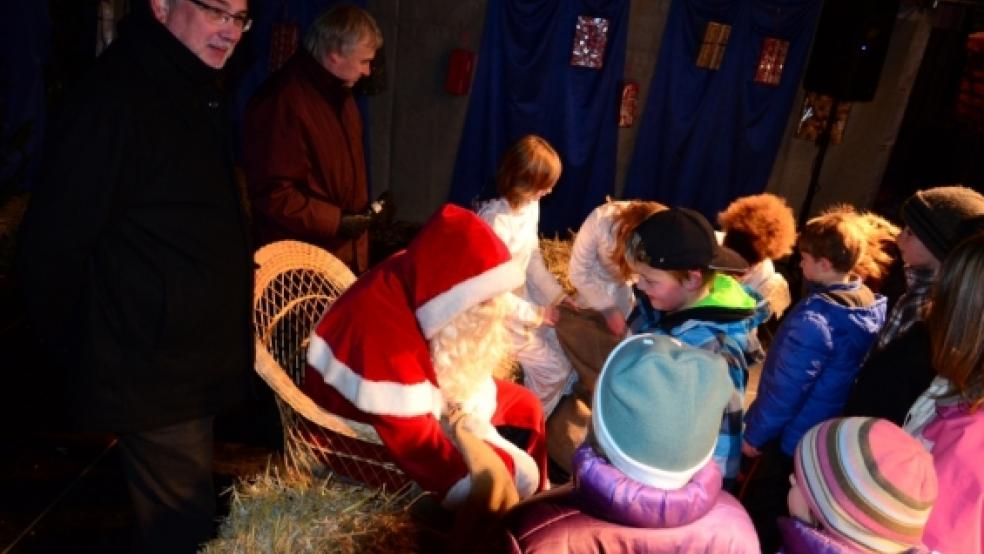 Ein Lächeln huschte nicht nur den vom Nikolaus beschenkten Kindern über das Gesicht. Auch der stellvertretende Bürgermeister Karlheinz Hinderks (links) und Evert Pastoor (Werbegemeinschaft Weener) freuten sich über den Ansturm der Kinder. Die drei Weihnachtsengel im Hintergrund (weiße Kleider) halfen dem Nikolaus beim Verteilen. © Wübbena