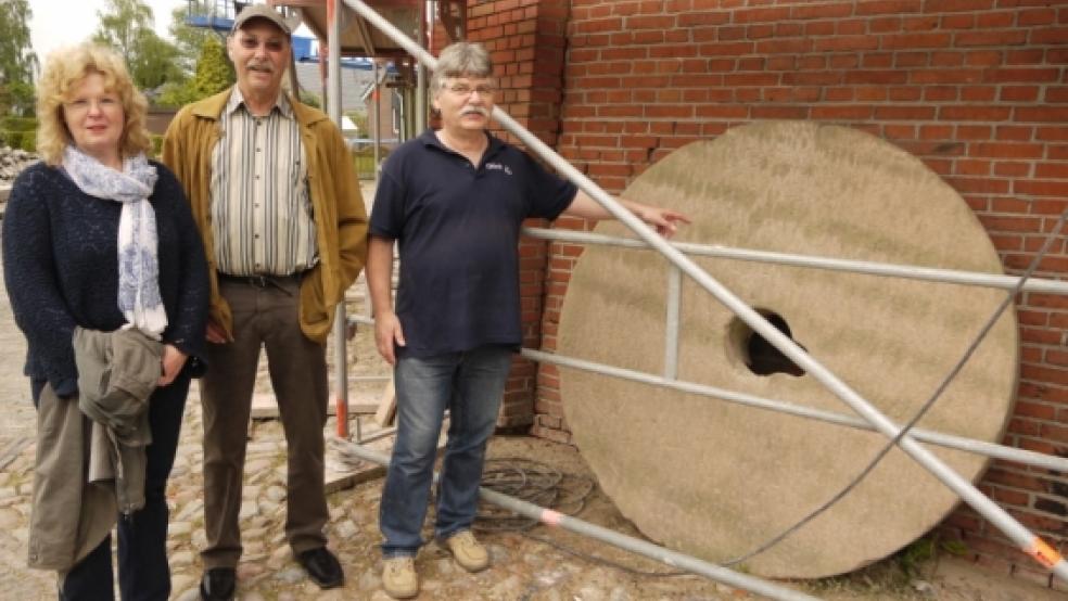 Ausgediente Mühlsteine wurden früher um die Mühle herum vergraben. Dieser alte Peldegang-Stein in Stapelmoor ist nun Zierde - und für Müller Manfred Gäbel der ideale Anfang einer Führung. Bernd und Hiltrud Berlage gefällt’s. © Foto: Himstedt
