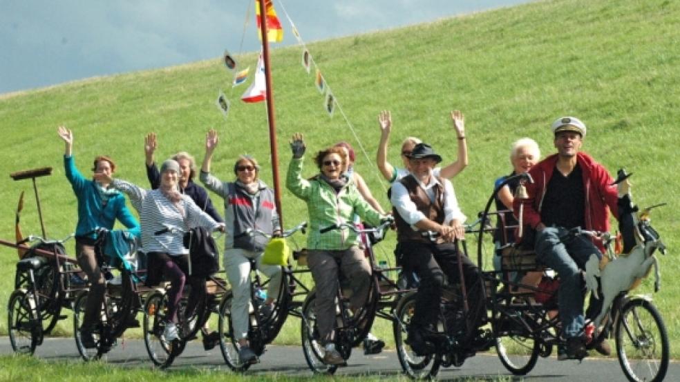 Kulturbotschafter on Tour am Emsdeich in Weener. Auch der Betreiber der Paddel- und Pedalstation, Norbert Deger (Dritter von rechts), trat auf den letzten Metern in die Pedale des »Fahrradschiffs«, mit dem sie von Oldenburg nach Groningen unterwegs sind. © Szyska