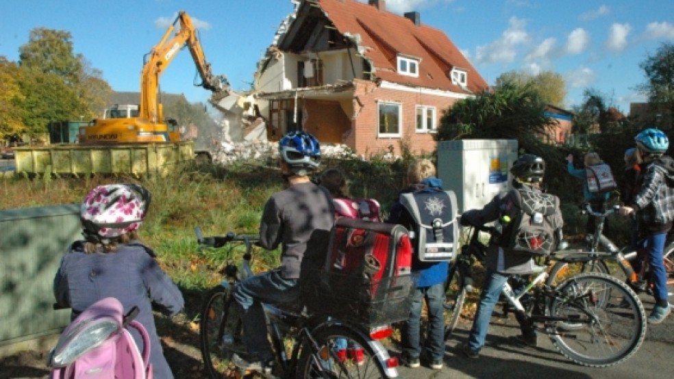 Viele Kinder aus der Grundschule und dem Kindergarten in Bingum verfolgten gestern gespannt, wie auf dem Nachbargrundstück der Abriss des städtischen Doppelhauses begann, das dem Neubau einer Förderschule der Spastikerhilfe weicht. Arbeiter des Lohnunternehmens Eiso Busemann aus Bunde werden damit auch heute noch beschäftigt sein. © Szyska