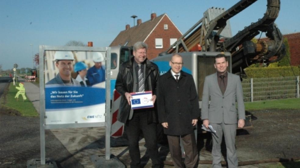 Der Anfang ist gemacht: Bürgermeister Johann Tempel mit den EWE-Vertretern Rainer Raddau und Gerrit Pruss (von links) an der Kreisstraße K 36 in Holtgaste, wo gestern im Horizontalbohrverfahren der Internet-Breitbandausbau begann. © Foto: Szyska