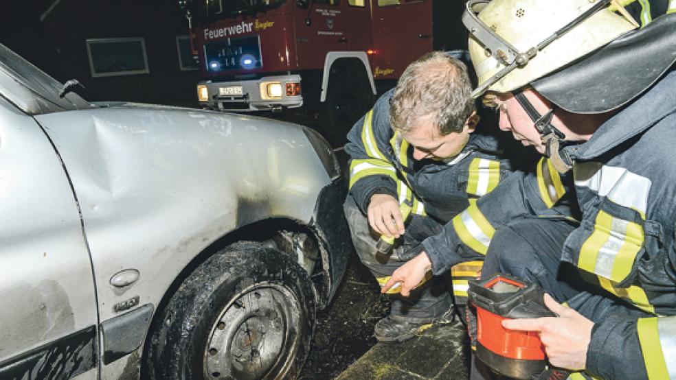 Feuerwehrleute nehmen den Radkasten des Wagens in Augenschein, der durch ein Feuer beschädigt wurde. Der Dauerparker an der Graf-Edzard-Straße sorgt seit Monaten für Unmut - rein rechtlich ist er auf der sicheren Seite. © Foto: Bruins