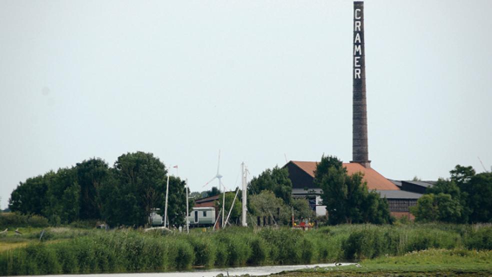 Die Ziegelei Cramer und der Yachthafen in Midlum von der Ems aus gesehen. Dunkle Wolken sind über das Areal gezogen. Nach dem Scheitern von Pachtverhandlungen bereitet der Landkreis ein Verbot von Nutzungen vor. © Foto: Hanken