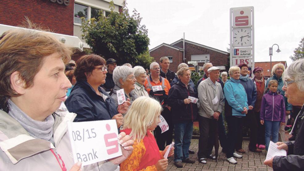 Mit Protest-Fähnchen haben mehr als 150 Einwohner und Kunden zum dritten Mal am Montagabend vor der Sparkasse in Bingum gegen die geplante Schließung demonstriert. Am Samstag ist erstmals eine Großdemonstration um 11 Uhr auf dem Denkmals­platz in Leer geplant. © Foto: Boelmann