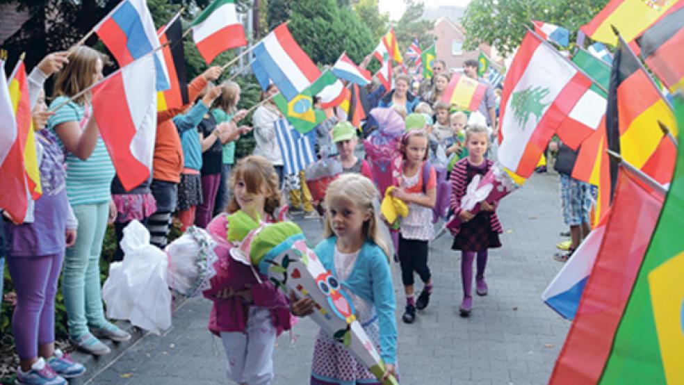 Farbenfroher Einzug in die Grundschule Weener: Mit einem Spalier aus bunten Fahnen empfingen Mitschüler und Lehrer die ABC-Schützen. © Foto: Hanken