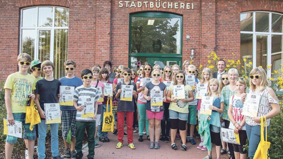 Stolz und mit Sonnenbrille präsentieren die Julius-Club-Kinder vor der Stadtbücherei ihre Diplome. © Foto: de Winter