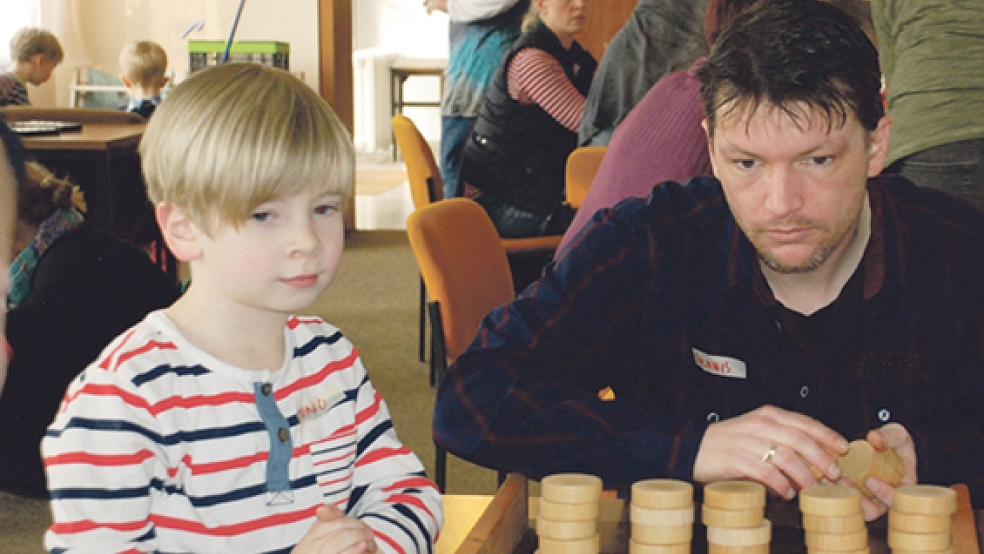 Dennis zeigt dem jungen Pogumer Janno die Tricks bei dem Geschicklichkeitsspiel »Sjoelbak«, das vor allem in den Niederlanden bekannt ist.  © 