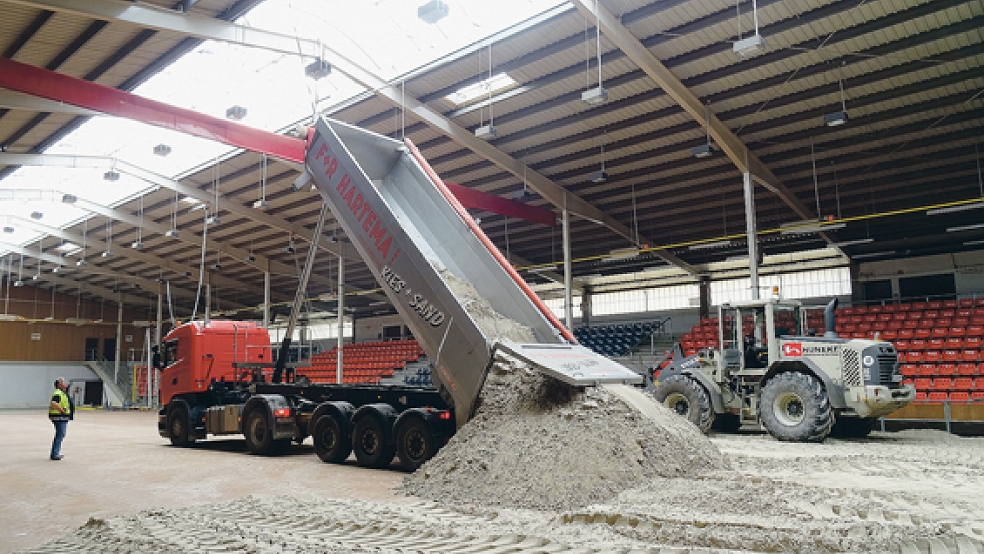 Mit schwerem Gerät werden in der Ostfrieslandhalle die etwa 300 Kubikmeter Sand für das Beachvollevballturnier verarbeitet. © Foto: privat