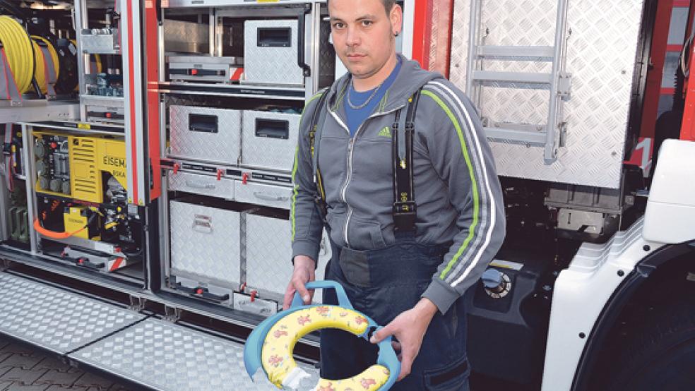 Geschafft: Gruppenführer Stefan Schröder mit dem Kindertoilettensitz, den er zuvor gemeinsam mit seiner Mannschaft vom Hals eines kleinen Jungen abgeschnitten hat. © Foto: Weege