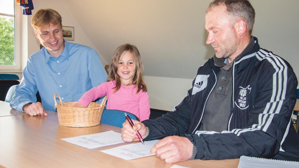 Glücksfee Maya Schneider zog bei der Auslosung des Rheiderland-Pokals die Paarungen. Jens Duin (links) und Hartmut Sinning sorgten dafür, dass alles seine Richtigkeit hat. © Foto: de Winter