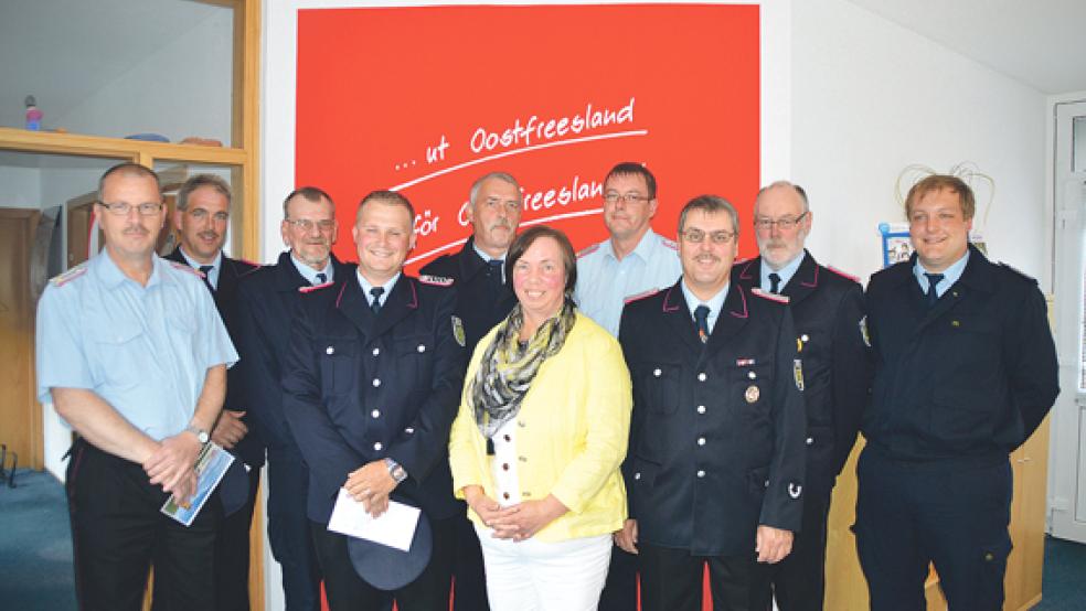 Hilde van Hoorn mit den Feuerwehrkameraden (von rechts) Andre Buß (Dollart), Meinert Waldecker (Ditzum), Gert Kuiper (Hatzum), Hans-Hermann Leemhuis (Bunde), Bernhard Albers (Jemgum), Johann Mühlena (Critzum), Andreas Mensing (Holtgaste), Tobias Stirler (Bunderhee) und Peter Lüppens (Wymeer/Boen).  © Foto: Himstedt