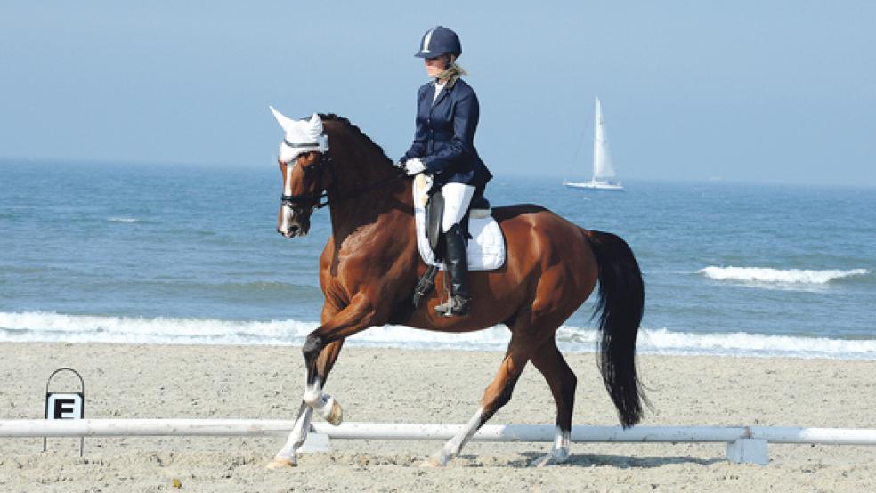 A-Dressur am Strand, während im Hintergrund die Segelyachten die Nordseeinsel Norderney passieren: Sara Wunsch (RFV Leer-Bingum) will auch in diesem Jahr wieder vor der Traumkulisse reiten.  © Foto: Gleich