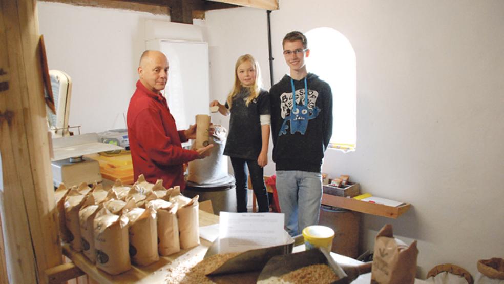 Flip Heinkens (links) vom Stapelmoorer Mühlenverein füllt das Speckendickenmehl in Papiertüten. Hedda und Markus, sie gehören zur dritten Generation der Familie Wichers, helfen dabei. © Foto: Kuper