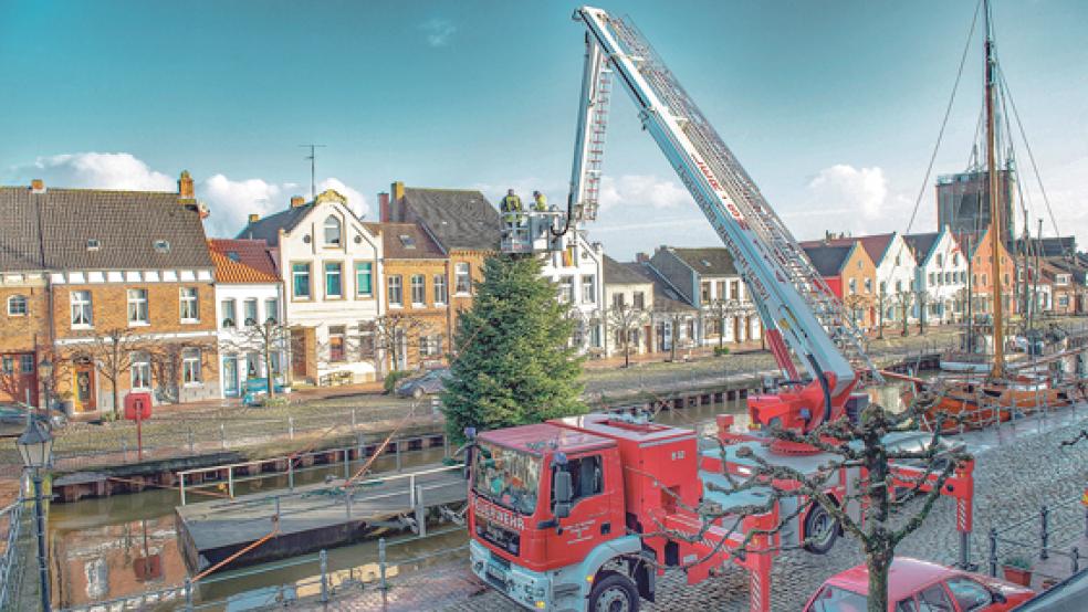 Jetzt wird es weihnachtlich am Alten Hafen in Weener: Hafenmeister Heiner Düring und Frank Klaaßen schmückten am Sonnabend mit Hilfe der Hubrettungsbühne der Freiwilligen Feuerwehr diesen schönen Tannenbaum auf dem wohl größen »Christbaumständer« weit und breit. Der Weihnachtsbaum erstrahlt nun allabendlich hell im Lichterglanz. © Foto: Bruins