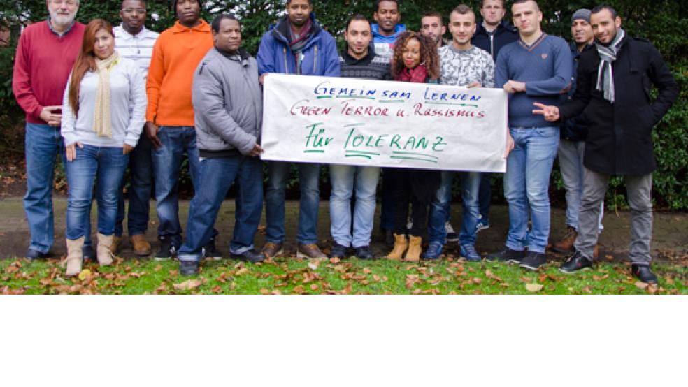 Dozent Reinhard Block (links) wirbt mit den Teilnehmern aus dem Einstiegskurs »Deutsch« mit einem Plakat für mehr Toleranz und gegen Terror und Rassismus.  © Foto: Volkshochschule 