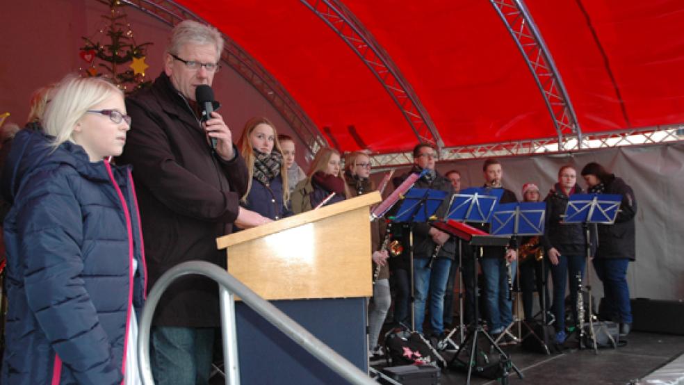 Mit »Weihnachtsengel« Alina Pastoor (links) eröffnete Bürgermeister Ludwig Sonnenberg den Adventsmarkt in Weener. Anschließend folgte mit Ratsmitgliedern und Mitarbeitern der Stadtverwaltung ein Rundgang, bei dem Sonnenberg an den Ständen entlang des Alten Hafens eine Kerze entzündete. © Foto: Szyska
