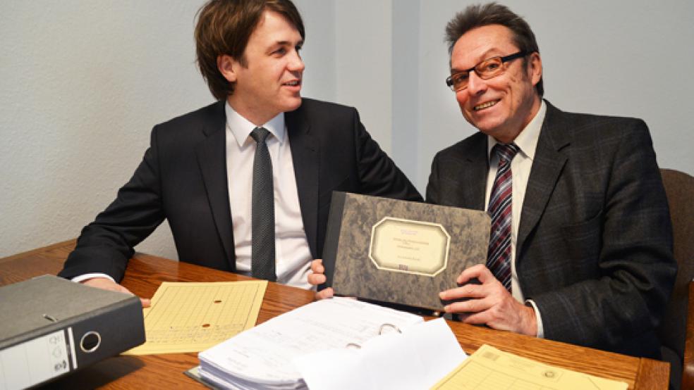 Bertus Baumeister (rechts) hält die Haushaltsrechnungen von 1970 in den Händen, als seine Karriere beim Landkreis Leer begann. Volumen damals: 50 Millionen D-Mark. Heute sind es rund 300 Millionen Euro. Links sein Nachfolger im Amt, Andre Willems. © Foto: Landkreis Leer