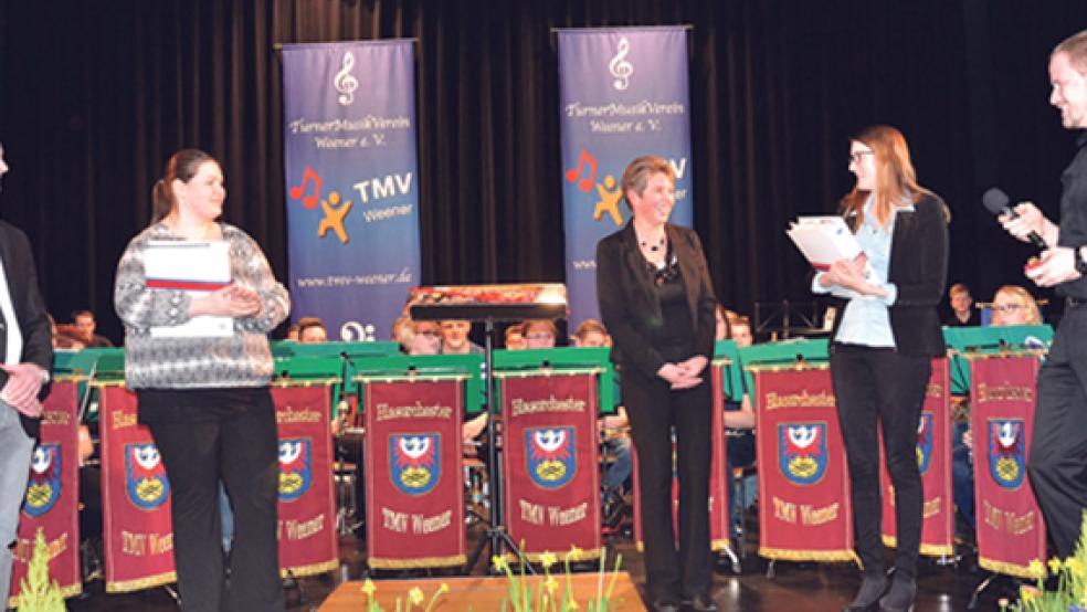 Stabwechsel beim TurnerMusikVerein: Der 1. Vorsitzende Jan Kuiper (rechts) und der 2. Vorsitzende Ingo Schmidt (links) verabschiedeten Heidi Giese (Bildmitte) als langjährige Dirigentin des Flöten- und des Jugendorchesters. Ihren Nachfolgerinnen Sonja de Buhr (Zweite von links) und Ina Giese (Zweite von rechts) überreichte sie schon einmal symbolisch dicke Aktenordner mit Partituren von mehrstimmigen Musikstücken. © Leserfoto: Heinrich Siemons