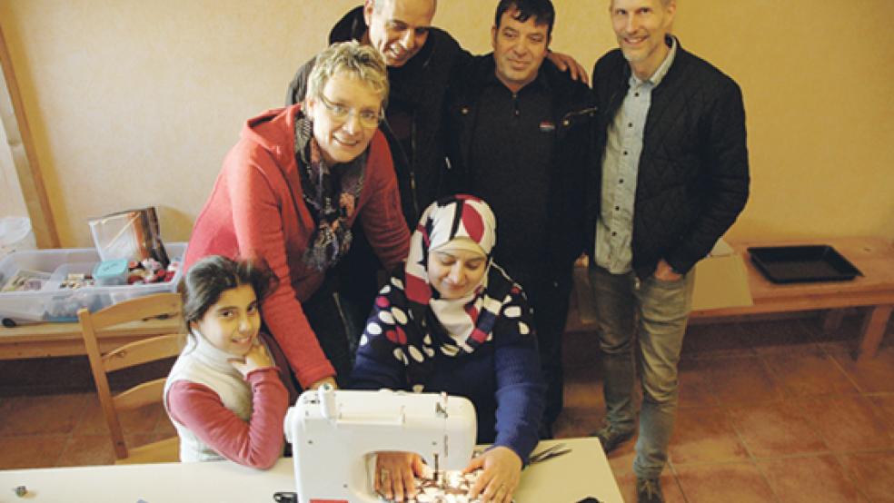 Initiatorin Sylke Schulte schaut Imen aus Syrien dabei zu, wie sie eine Stofftasche näht. Auch die kleine Sydra (links) sowie (stehend von links) ihr Vater Ahmed aus Damaskus, Imens Ehemann Khaled und Pastor Marco Kassebaum freuen sich über das neue Angebot. Der kostenlose Näh- und Kreativkurs steht nicht nur Flüchtlingen offen, sondern allen Interessierten. © 