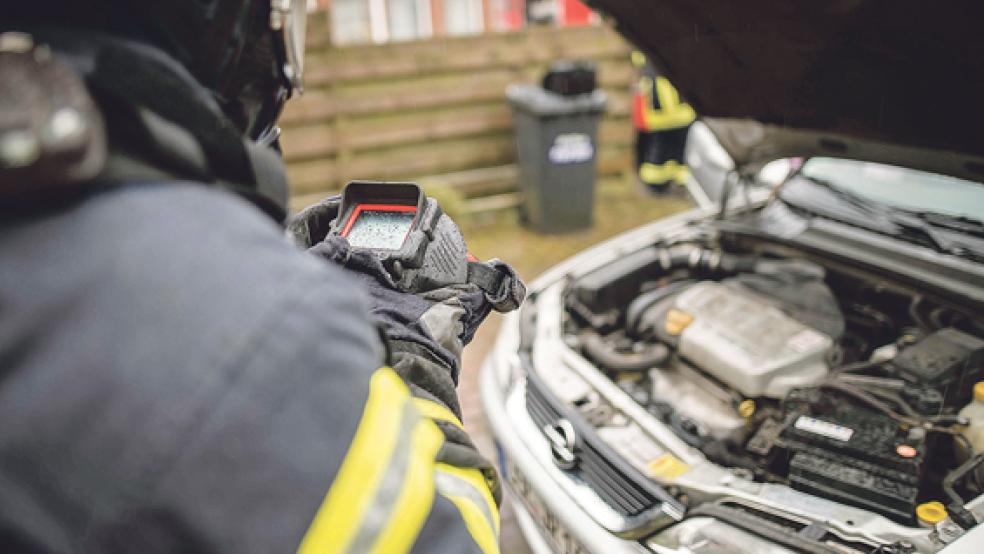 Mit einer Wärmebildkamera kontrolliert ein Feuerwehrmann nach einem Autobrand an der Neuen Straße in Weener den Motorraum des betroffenen Wagens. © Foto: Klemmer