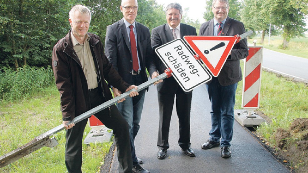 Die Radwegschäden gehören der Vergangenheit an: Bürgermeister Gerd Conens, Fachbereichsleiter Detlev Thieke, Landrat Reinhard Winter und 1. stellvertretender Bürgermeister Gerhard Husmann (von links) entfernen das Verkehrsschild, das Radfahrer vor einer schadhaften Wegstrecke warnte.  © Foto: Landkreis Emsland 