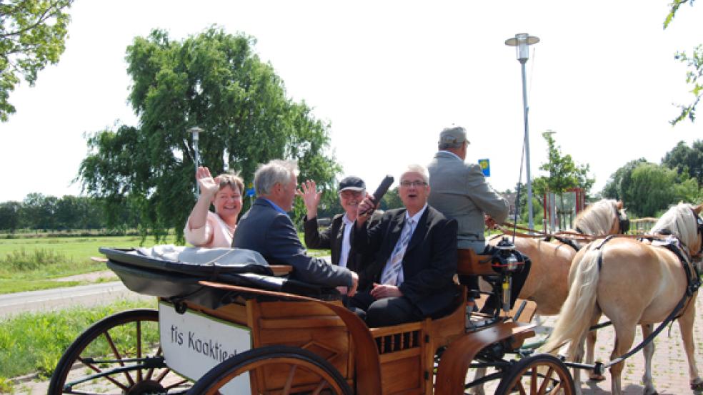 Aus der Kutsche grüßen Pastorin Anne Ulferts, Wilfried Hoffbauer und Karlheinz Hinderks (von links). Vorne links Cornelius Barth, Kirchenratsvorsitzender von St. Georgiwold.  © Foto: Hoegen