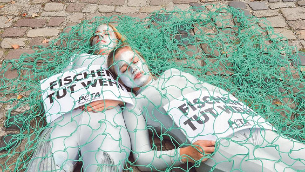 Julia und Alena Thielert von der Tierrechtsorganisation »Peta« haben heute in Leer am Hafen demonstriert. Als »Leichen« im Fischernetz machten die Geschwister auf das Leid der Fische aufmerksam.  © Foto: Boelmann