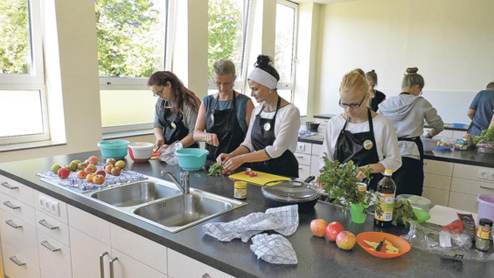Gerda Mülder (zweite von links), Gitta Connemann (dritte von links) und zwei Schülerinnen beim Gemüseschneiden für die »Bunten Bratkartoffeln«. © Foto: Muising