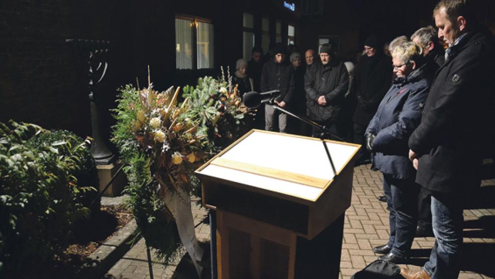 Schweigend und mit gesenktem Kopf gedachten die Teilnehmer der Gedenkstunde den ermordeten Juden aus Weener am Menora-Denkmal.  © Foto: Tirrel