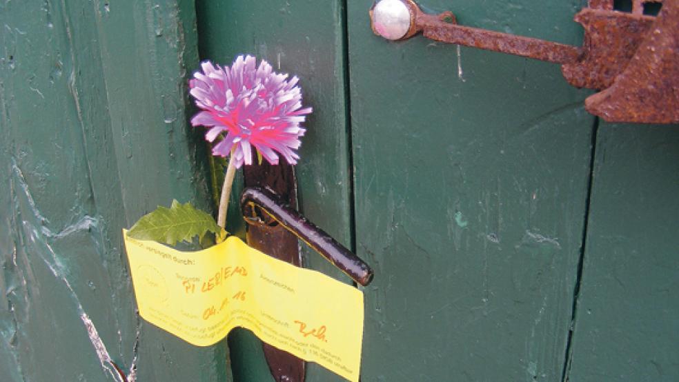 Am Café in Bingum erinnert eine Blume am polizeilichen Siegel an die Galeristin Gerda Basse. © Foto: Szyska