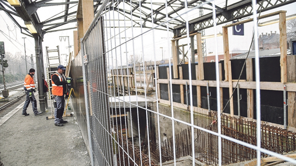 Zwei Männer arbeiten am Bahnhof in Leer an der denkmalgeschützten Dachkonstruktion über dem Mittelbahnsteig. Sanierungsbedürftige Teile sollen in einem Werk aufgearbeitet werden. Auch die Arbeiten an der neuen Unterführung, die zwei Fahrstühle bekommt, gehen weiter.  © Foto: Wieking