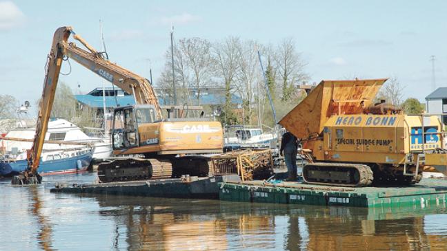 Bagger holt Schlick aus dem Hafen