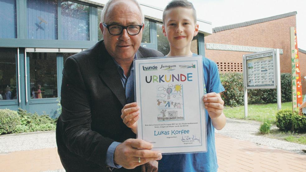 Stolz hält Lukas Korfee aus Weener gemeinsam mit Jemgums Bürgermeister Hans-Peter Heikens seine Urkunde in die Kamera. Das Bild des Zehnjährigen wurde von einer Jury als Titelbild für den Rheiderland-Ferienpass 2017 ausgewählt. © Foto: Szyska