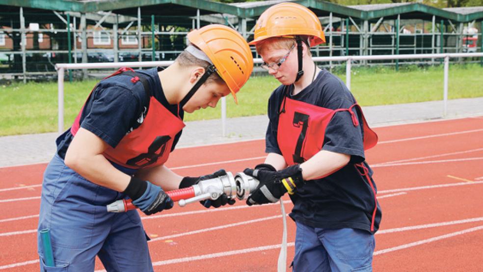 Beim Wettbewerb: Julian und Sören von der Jugendfeuerwehr Jemgum kuppeln einen C-Schlauch mit einem Strahlrohr zusammen, bevor sie einen Knoten mit der Feuerwehr­sicherheitsleine anlegen.  © Foto: Loger