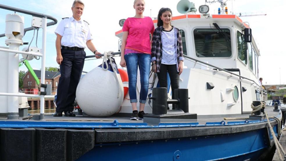 Der Leiter der Wasserschutzpolizei Emden, Polizeihauptkommissar Jörg Fels-Hohensee, mit Ayline Lorna Heitmeyer und Shahd Hammoud an Bord des Polizeibootes. © Foto: Polizei