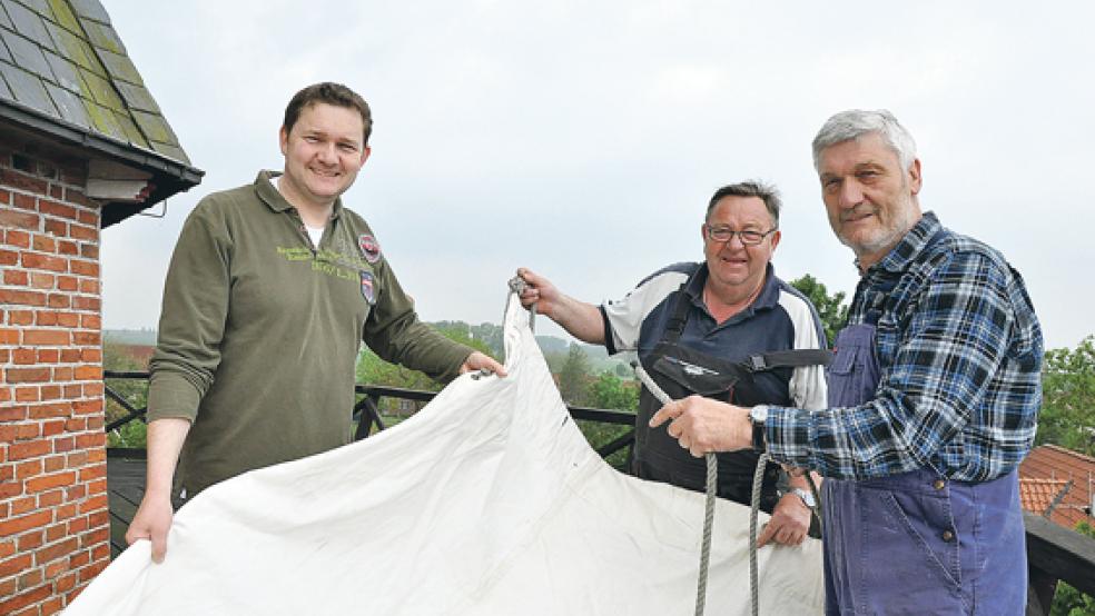 Die freiwilligen Müller Rolf Glazenburg, Hermann Oltmanns und Johann Glazenburg haben gestern Vormittag vier Kunststoffsegel über die weißen Flügel gezogen, damit auch bei nur wenig Wind Getreide gemahlen werden kann. © Fotos: Boelmann