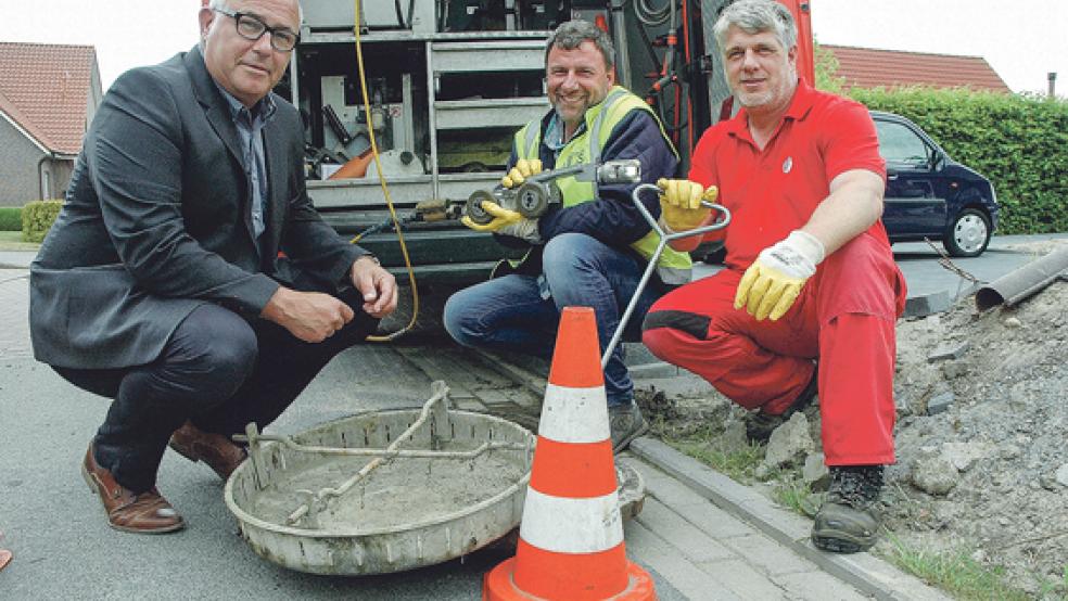Blick in den Schacht in der Nesser Straße in Jemgum: Bürgermeister Hans-Peter Heikens, Diplom-Ingenieur Joachim Papesch (ITAS GmbH aus Salzgitter) mit der Spezialkamera in der Hand und Olaf Mienack (Canal Control GmbH aus Barsbüttel, von links). © Foto: Szyska
