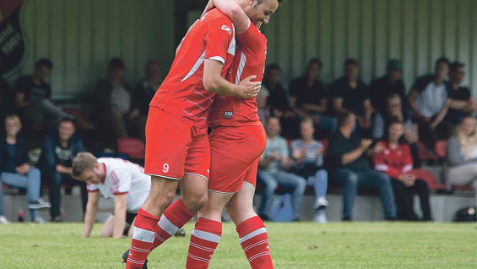 Bunde liegt sich in den Armen, Großefehn ist am Boden: Nach dem 3:0 freuen sich Malte Troff und Marco Borchers, während ihr Gegenspieler (im Hintergrund) den Abstieg nicht fassen kann. © Fotos: Mentrup