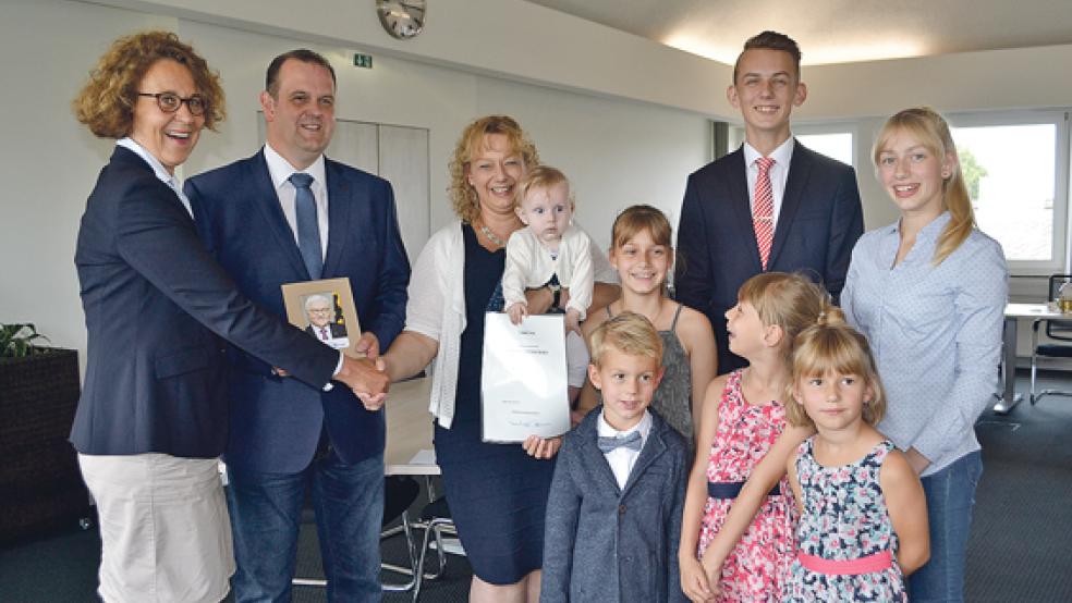 Die Patenschschaftsurkunde und ein Bild von Bundespräsident Frank-Walter Steinmeier überreicht Bürgermeisterin Beatrix Kuhl an Anke Hilbrands, die die kleine Magdalena auf dem Arm hält. Neben ihr ihr Ehemann Michael. Neben Magdalena Hilbrands haben sich ihre sechs Geschwister gruppiert. © Foto: Stadt Leer