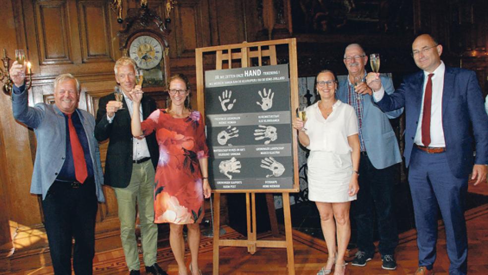 Die Deputierte der Provinz Groningen, Nienke Homan (Dritte von links), und Vertreter der fünf anderen Teilnehmer des Schlick-Projektes an Ems und Dollart bestätigten mit einem Handabdruck aus Klei und einem Glas Sekt die Zusammenarbeit. © Foto: Kuper
