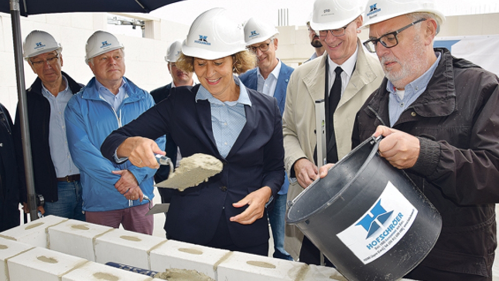 Bürgermeisterin Beatrix Kuhl (CDU) packte gestern Vormittag bei der Grundsteinlegung für das neue Hallenbad in Leer mit an. In alter Tradition wurde auch eine Zeitkapsel im Mauerwerk versenkt. © Foto: Stadt Leer